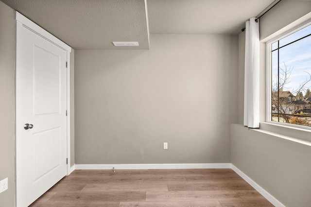 empty room with a healthy amount of sunlight, baseboards, and wood finished floors