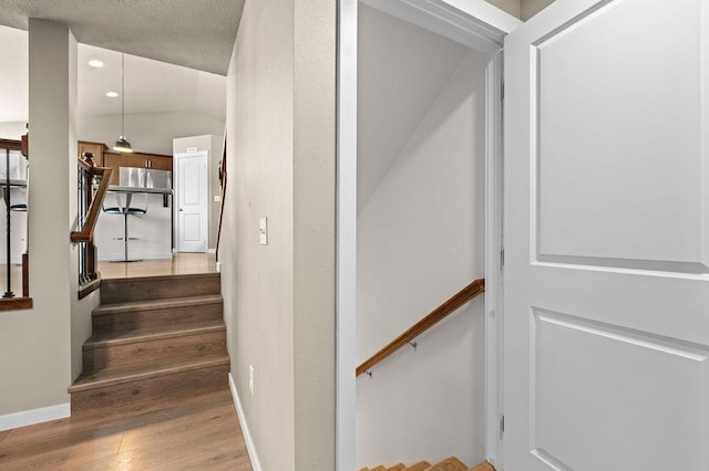 stairs with baseboards, wood finished floors, and recessed lighting