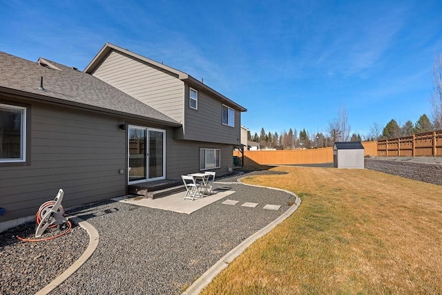 back of house featuring a shingled roof, a lawn, an outbuilding, fence, and a patio area