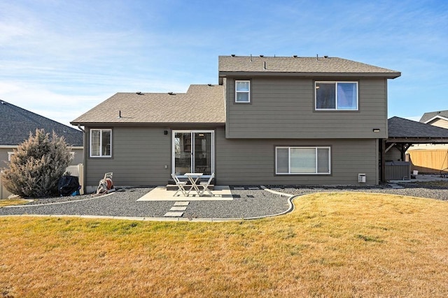 back of property with a patio area, roof with shingles, and a yard