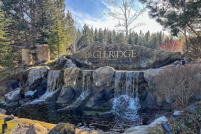 community / neighborhood sign featuring a view of trees