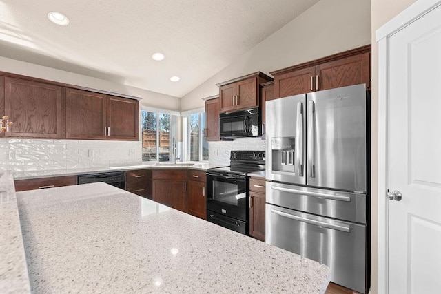 kitchen featuring light stone counters, tasteful backsplash, lofted ceiling, a sink, and black appliances