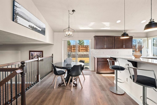 dining area with light wood-type flooring, a notable chandelier, a wealth of natural light, and recessed lighting