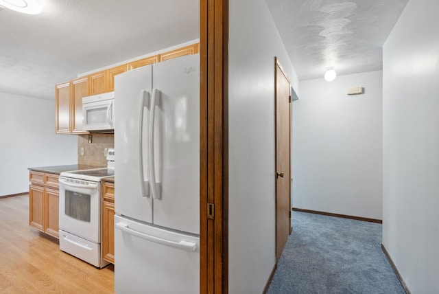 kitchen with white appliances, backsplash, light colored carpet, and baseboards