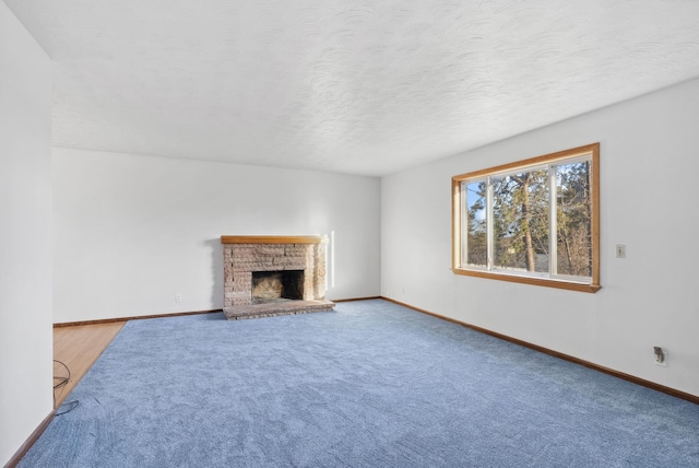 unfurnished living room with carpet floors, a brick fireplace, baseboards, and a textured ceiling