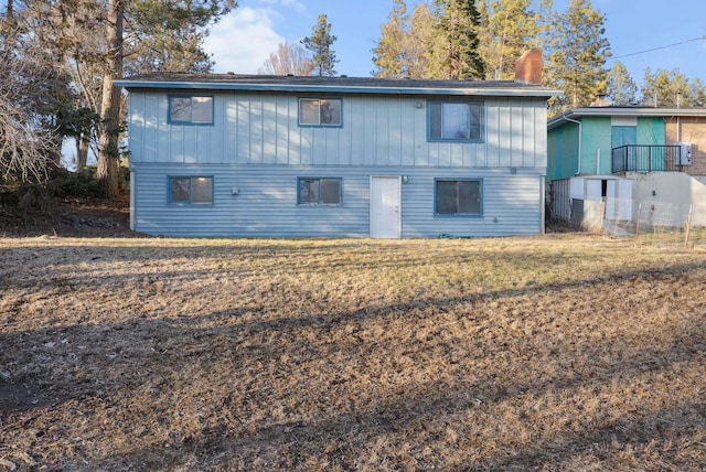 rear view of house with a yard, a chimney, and board and batten siding