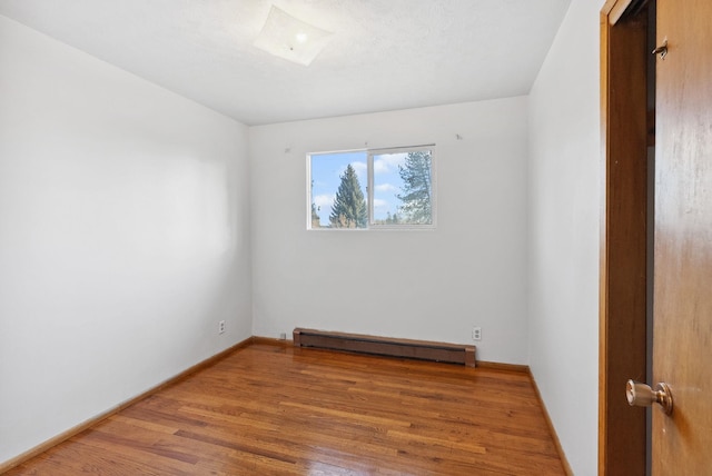 unfurnished room with light wood finished floors, a baseboard radiator, and baseboards