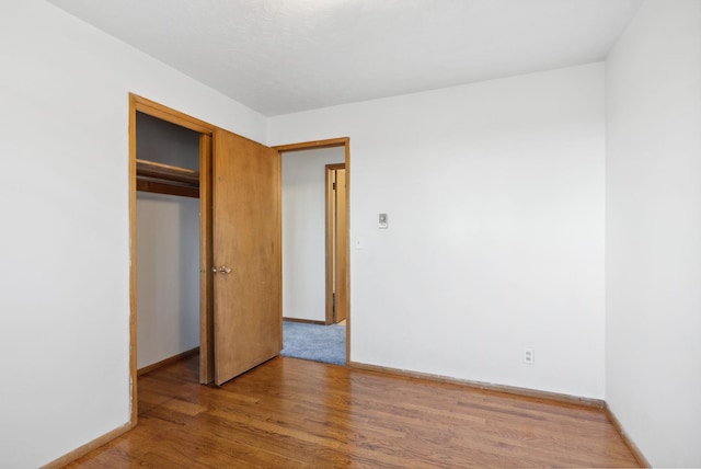 unfurnished bedroom featuring a closet, wood finished floors, and baseboards