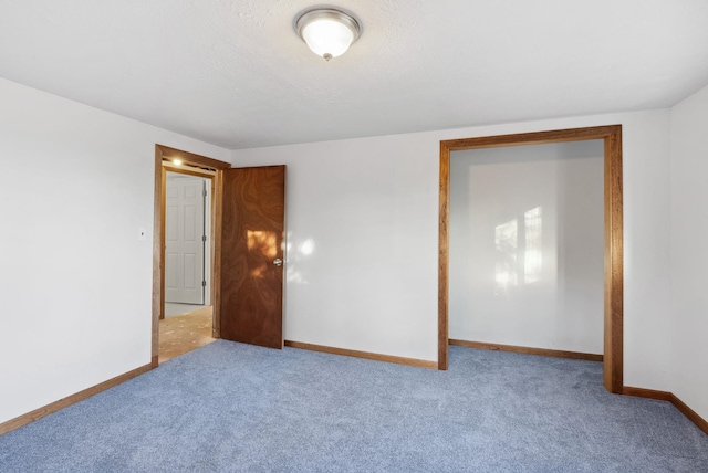 spare room with a textured ceiling, baseboards, and carpet flooring