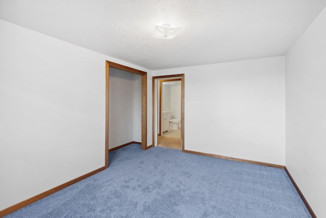 empty room with a textured ceiling, carpet floors, and baseboards