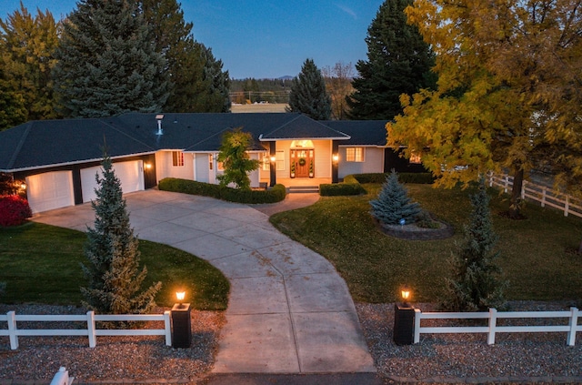 single story home featuring a garage, concrete driveway, a front lawn, and a fenced front yard