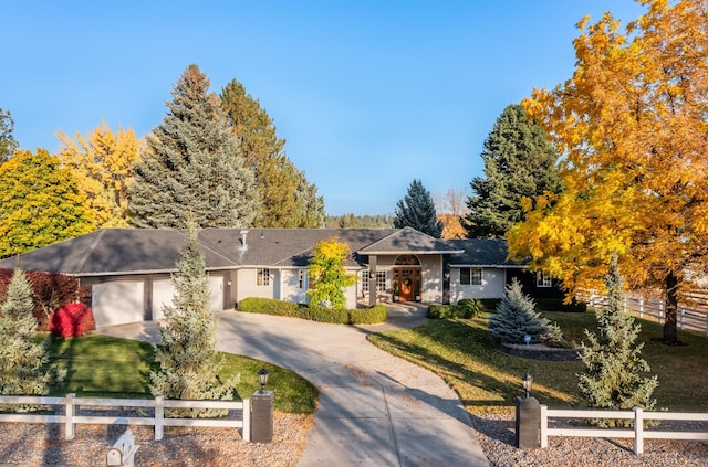 single story home featuring concrete driveway, a front lawn, a fenced front yard, and an attached garage