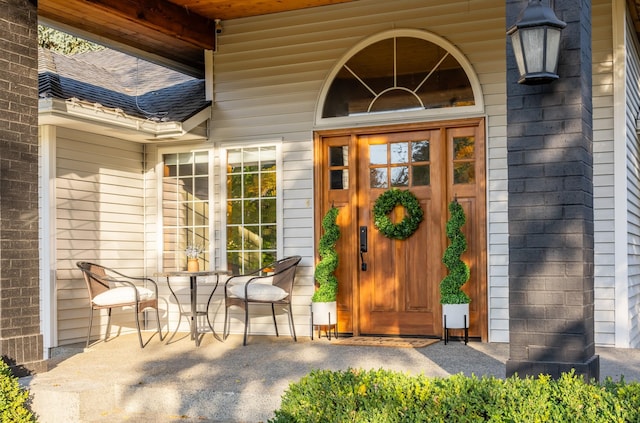 property entrance featuring a shingled roof and brick siding