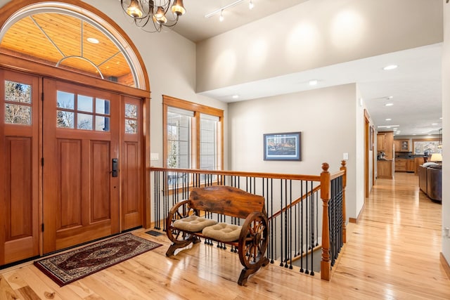 entrance foyer with a chandelier, recessed lighting, rail lighting, and light wood-style floors