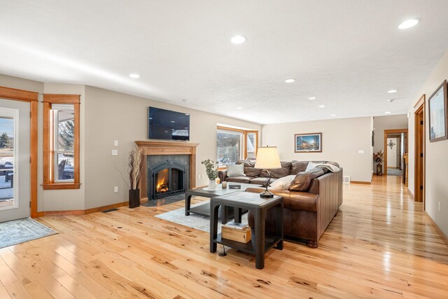 living area with light wood-type flooring, a high end fireplace, and recessed lighting