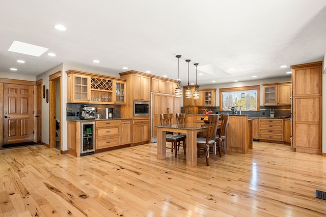 kitchen featuring a breakfast bar area, dark countertops, a kitchen island, built in appliances, and beverage cooler