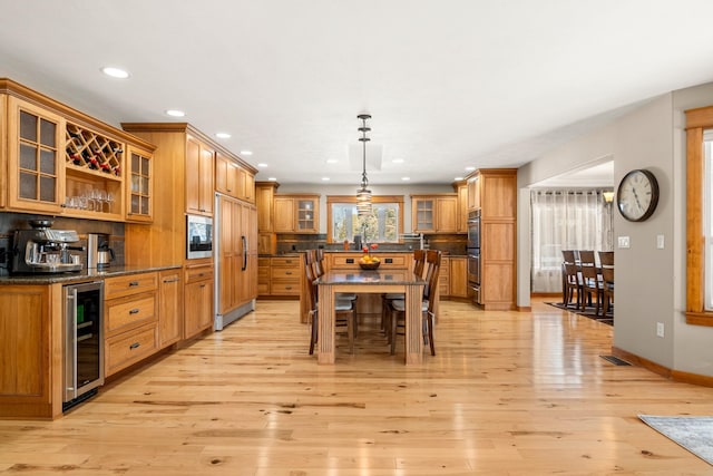 kitchen featuring a center island, visible vents, light wood-style flooring, built in appliances, and beverage cooler