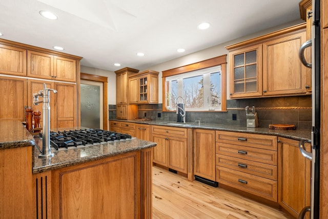 kitchen featuring dark stone counters, brown cabinets, a sink, and decorative backsplash