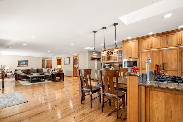 kitchen featuring recessed lighting, a breakfast bar, light wood-style floors, brown cabinets, and built in microwave