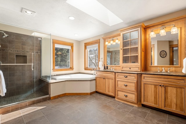 bathroom with a skylight, a sink, a shower stall, a bath, and double vanity