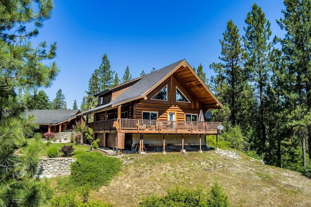 back of property featuring a deck, a yard, and log exterior