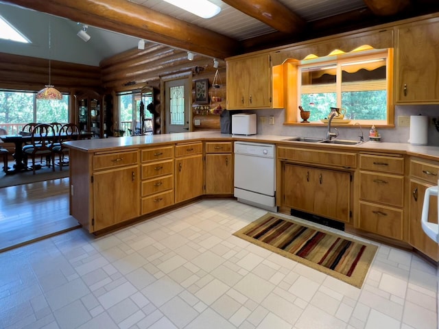 kitchen with beam ceiling, light countertops, white dishwasher, a sink, and a peninsula