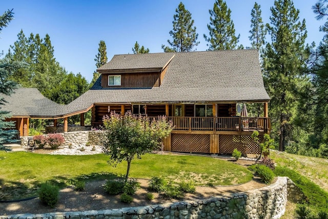 back of house featuring log siding, a deck, a lawn, and roof with shingles