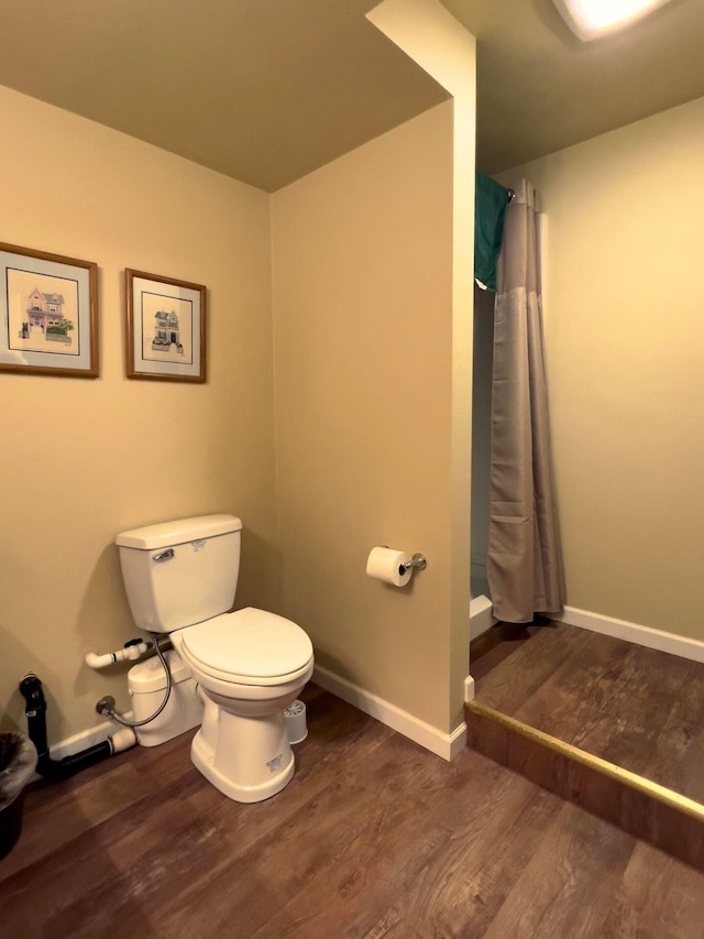 bathroom with curtained shower, baseboards, toilet, and wood finished floors