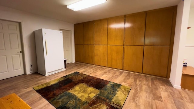 unfurnished bedroom featuring wood finished floors and freestanding refrigerator