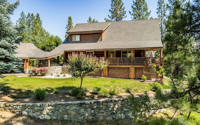 rear view of property featuring a yard and a shingled roof