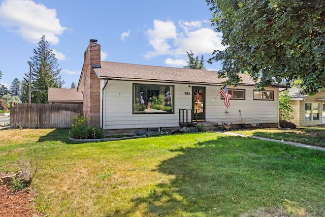 ranch-style house with fence, a chimney, and a front lawn