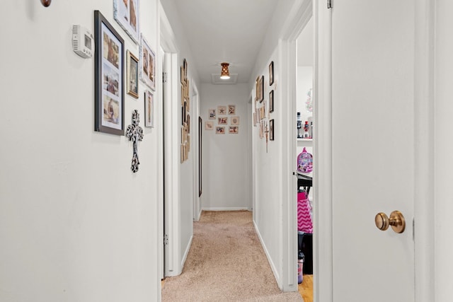 corridor with attic access, light carpet, and baseboards