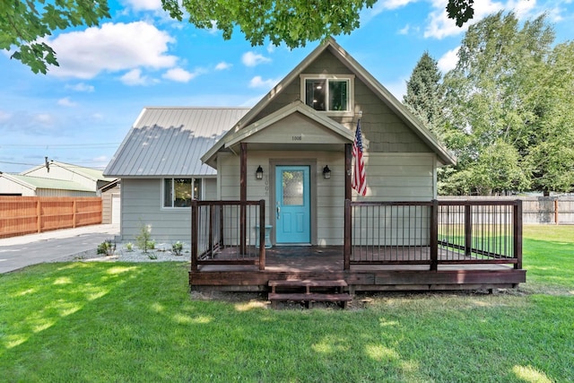 bungalow with a deck, metal roof, a front yard, and fence