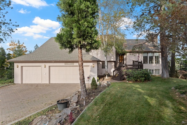 view of front facade featuring an attached garage, a shingled roof, a front lawn, and decorative driveway