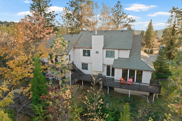 rear view of property with a deck and a shingled roof