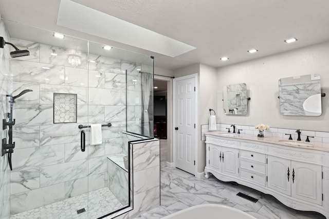 bathroom featuring marble finish floor, double vanity, a sink, and a shower stall