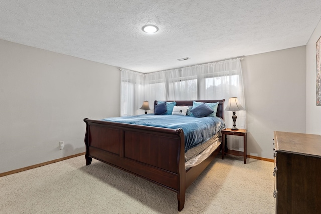 bedroom featuring light colored carpet, visible vents, baseboards, and a textured ceiling