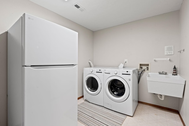 laundry room featuring light floors, independent washer and dryer, a sink, and visible vents