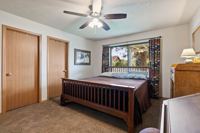 bedroom with a textured ceiling, carpet floors, two closets, and a ceiling fan