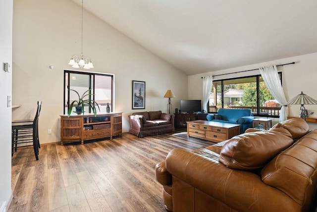 living area featuring baseboards, a notable chandelier, high vaulted ceiling, and wood finished floors