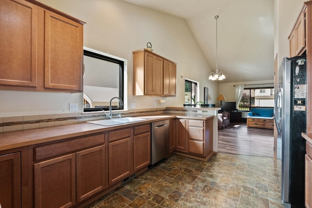 kitchen with a chandelier, a peninsula, a sink, open floor plan, and appliances with stainless steel finishes