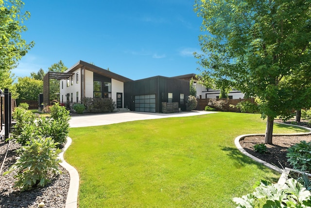 view of yard featuring a garage, concrete driveway, and fence