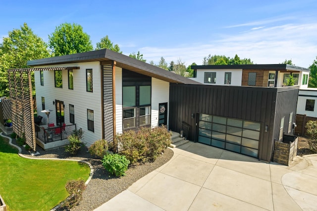 contemporary house with driveway, board and batten siding, an attached garage, and a front yard