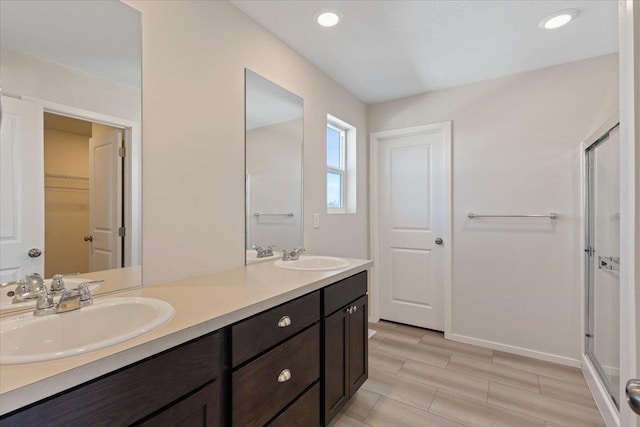 full bath with double vanity, a sink, a walk in closet, and a shower stall