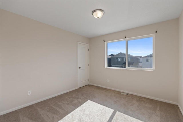 carpeted spare room featuring baseboards