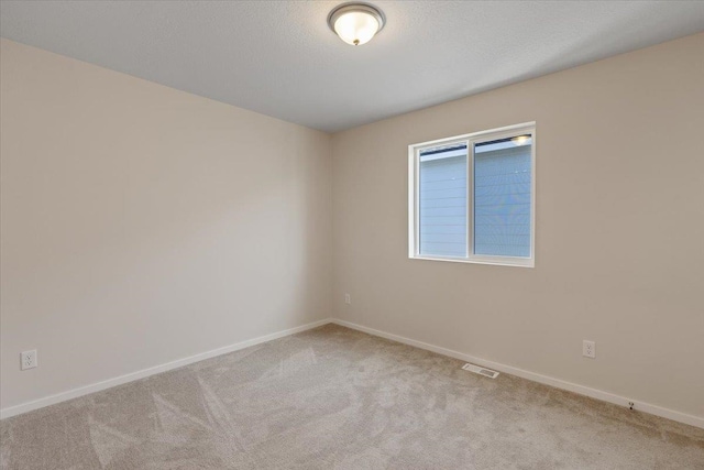 carpeted spare room featuring visible vents, a textured ceiling, and baseboards