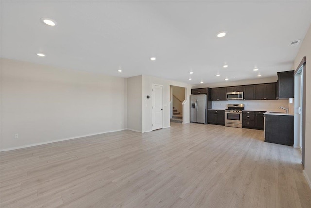 kitchen featuring light wood-style floors, stainless steel appliances, light countertops, and open floor plan