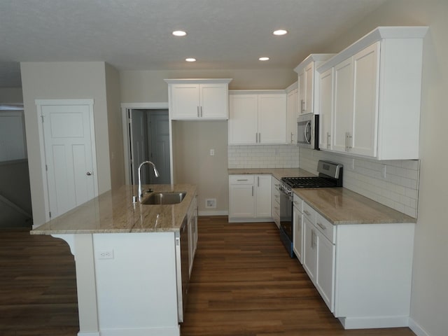 kitchen featuring light stone counters, a sink, white cabinets, range with gas stovetop, and stainless steel microwave