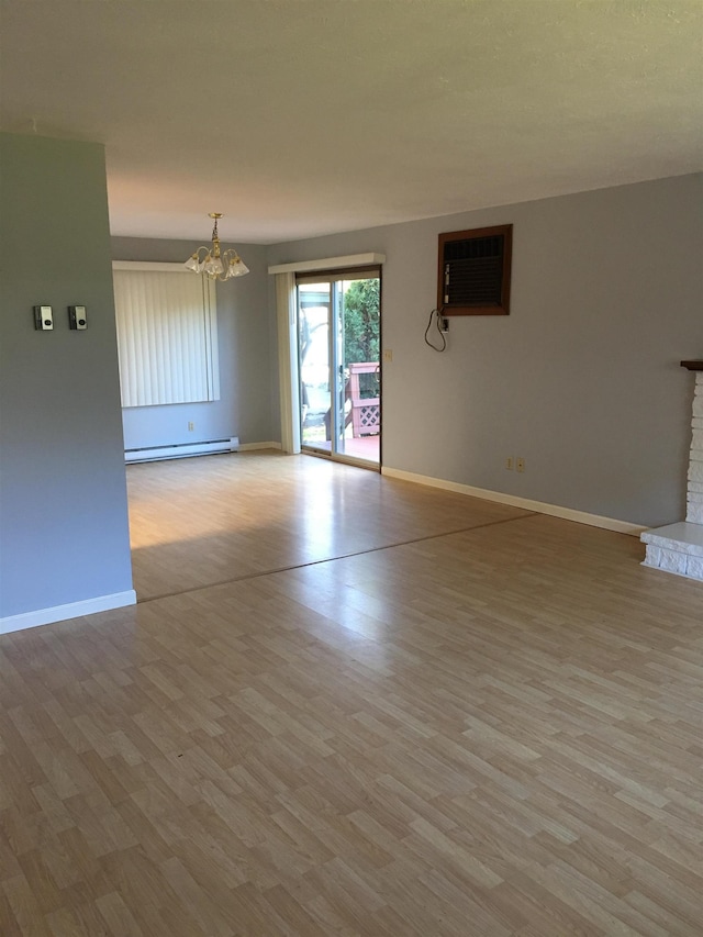 spare room with a wall unit AC, a baseboard heating unit, a chandelier, and wood finished floors