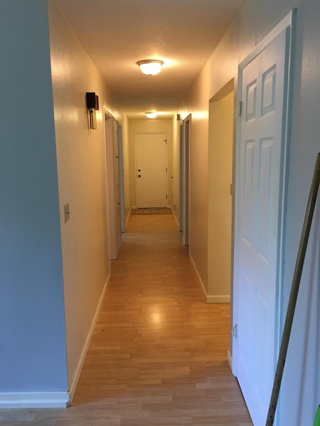 hallway featuring baseboards and light wood finished floors